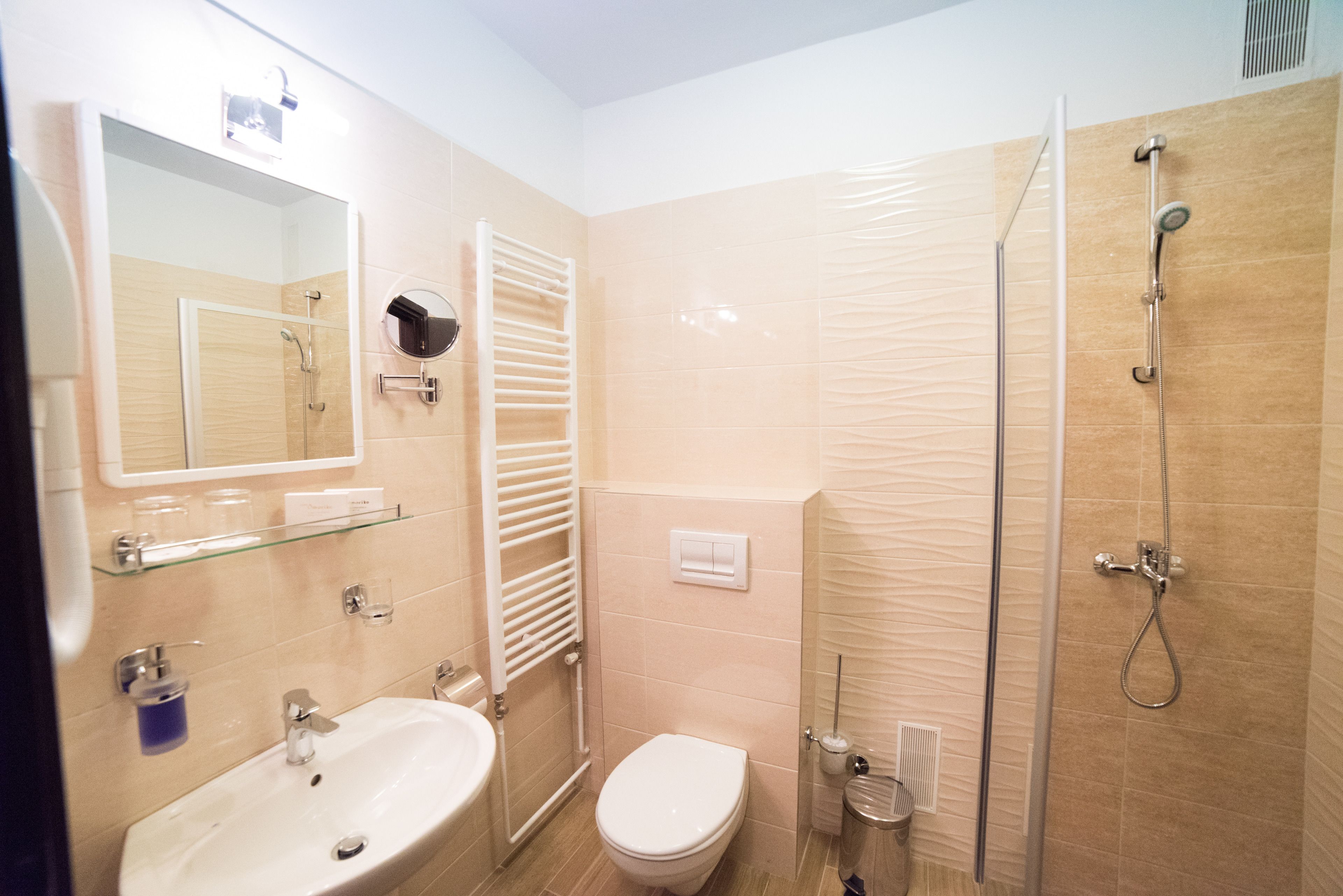 Un baño con lavamanos, inodoro y ducha con mampara de vidrio.