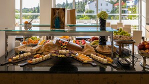 Een buffet met diverse gerechten en uitzicht op de stad door grote ramen.