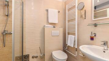 Un baño moderno con cabina de ducha de vidrio, inodoro, lavamanos y barra para toallas.