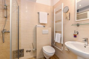 Un baño moderno con cabina de ducha de vidrio, inodoro, lavamanos y barra para toallas.