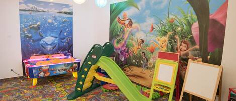 Un cuarto de juegos infantil con murales coloridos, una mesa de juegos y un juguete de mariquita.
