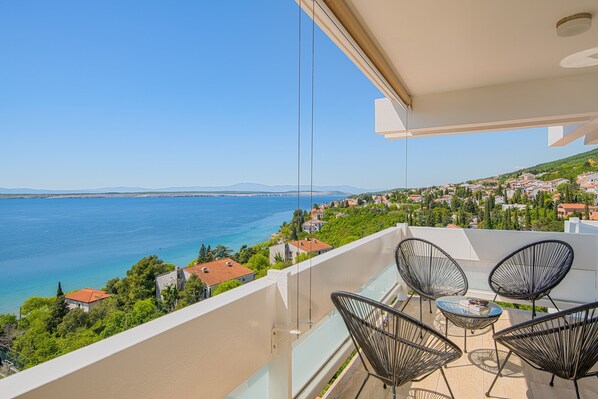 Un balcón con vista al mar y a un pueblo.