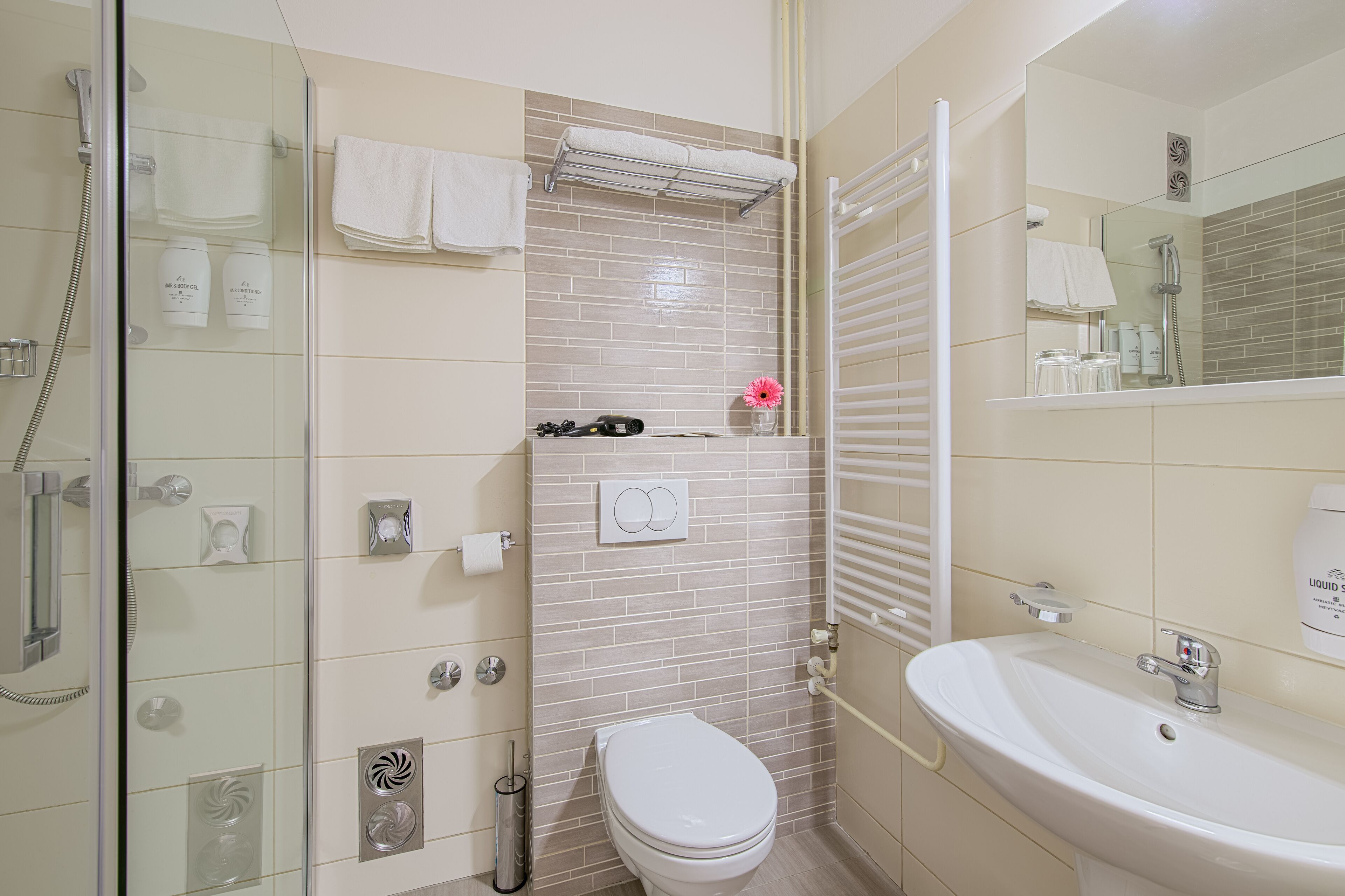 Un baño moderno con cabina de ducha de vidrio, inodoro blanco, lavamanos y toallero.