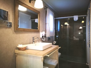 A bathroom with a sink, mirror, and shower.