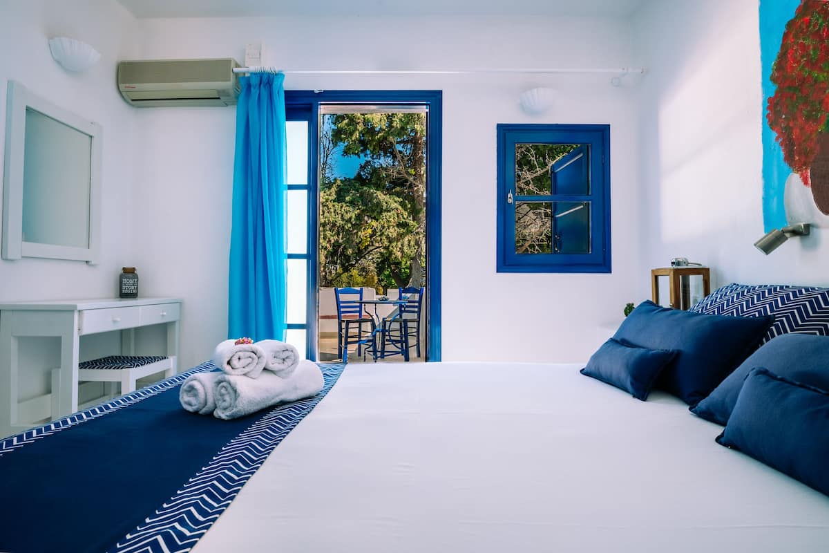 A hotel room with a bed, a desk, and a view of the outdoors.