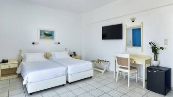 A hotel room with a bed, desk, chair, TV, and a small plant.
