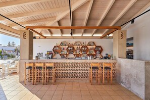 A bar area with wooden chairs and a counter displaying various bottles. - Hara Ilios Village (Hersonissos)