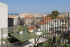 A balcony with a table, chairs, a bowl of fruit, a potted plant, and a menu. - Arkadi Hotel (Chania)
