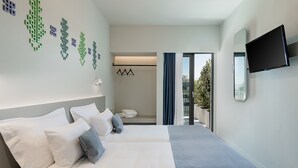 A modern hotel room with a large bed, a flat-screen TV, and a view of the outdoors. - Arkadi Hotel (Chania)