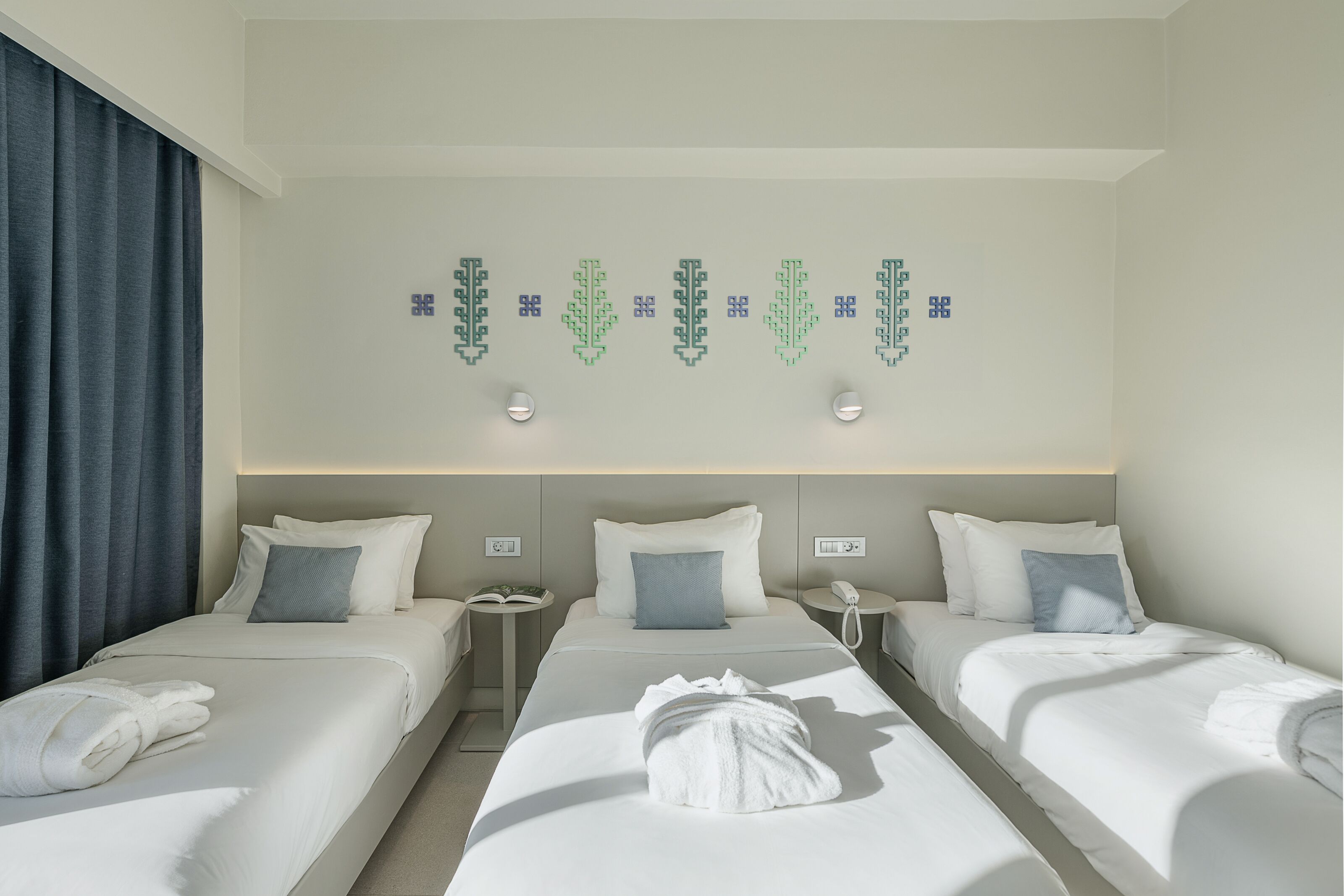 Una habitación de hotel con dos camas, una mesita de noche con teléfono y una lámpara fijada a la pared.