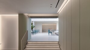 A modern interior with a staircase leading to a dining area with blue chairs and a table. - Arkadi Hotel (Chania)
