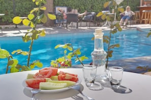 A table with a plate of watermelon and cucumber slices, a bottle of water, and two glasses. - Marirena (Malevizi)