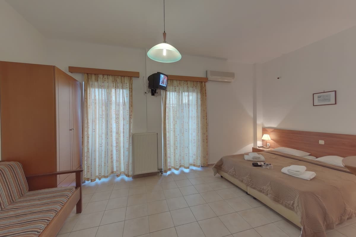 Una habitación de hotel con cama, sofá, televisor y radiador.