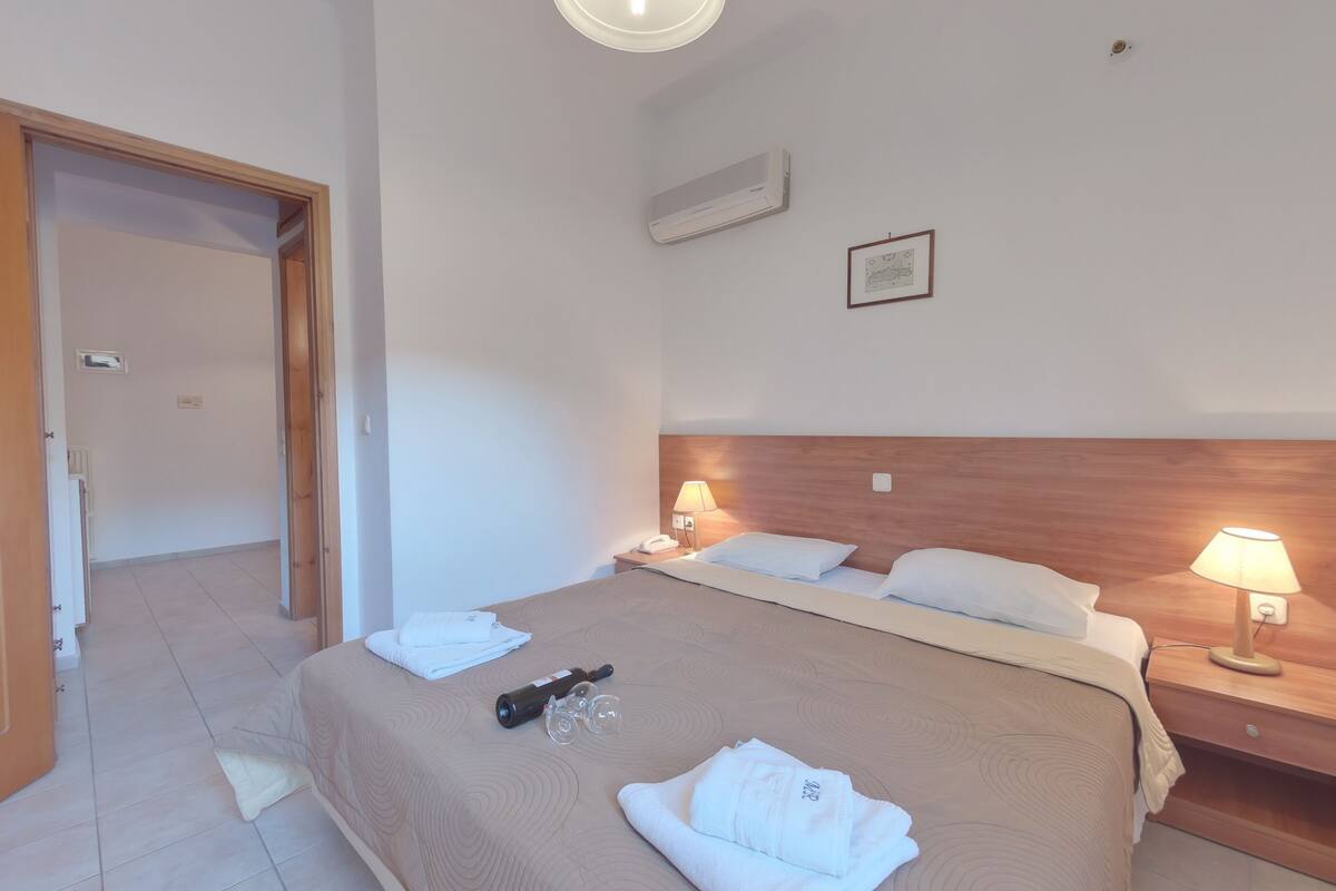 Habitación de hotel con cama, lámparas de noche, aire acondicionado en la pared y un cuadro enmarcado.