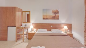 A bedroom with a bed, bedside tables, a desk, a chair, a wardrobe, and a refrigerator. - Marirena (Malevizi)