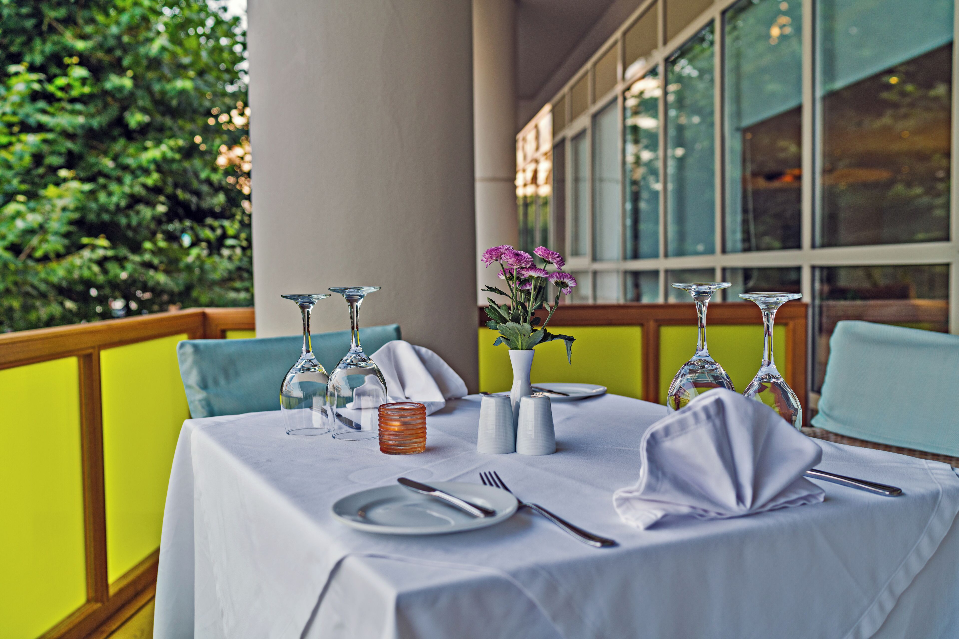A table set for dining with wine glasses, a vase with flowers, and a salt and pepper set.