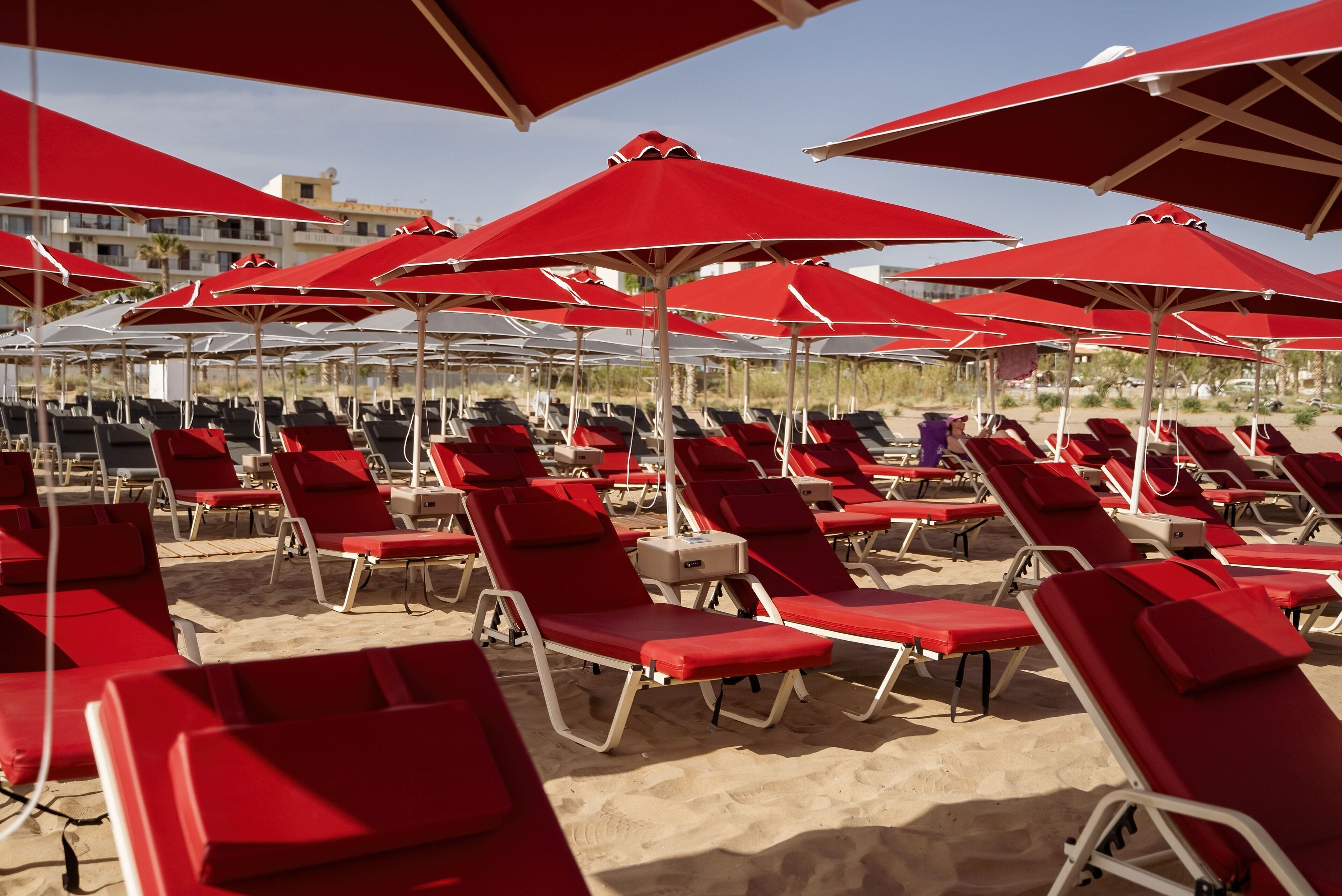Una playa con hileras de tumbonas rojas y sombrillas a juego.