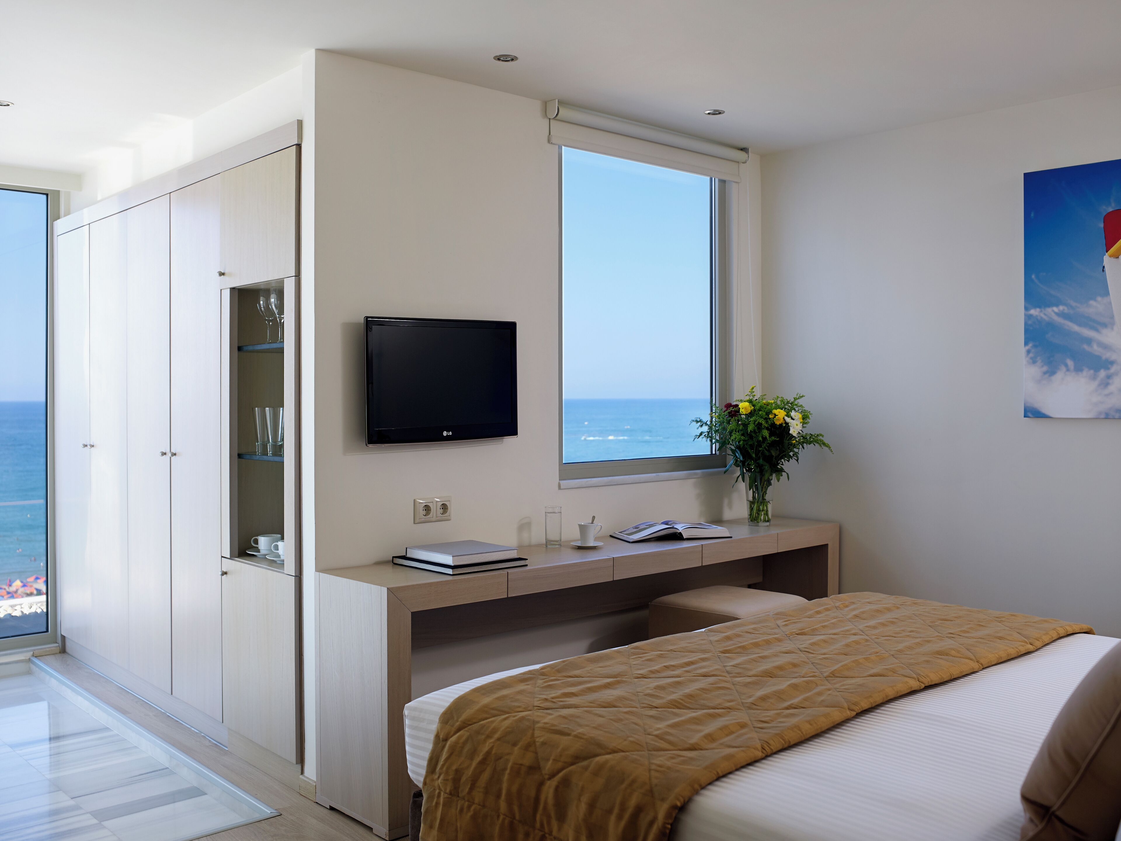 Une chambre moderne avec un lit, un bureau, une télévision et une fenêtre donnant sur la mer.