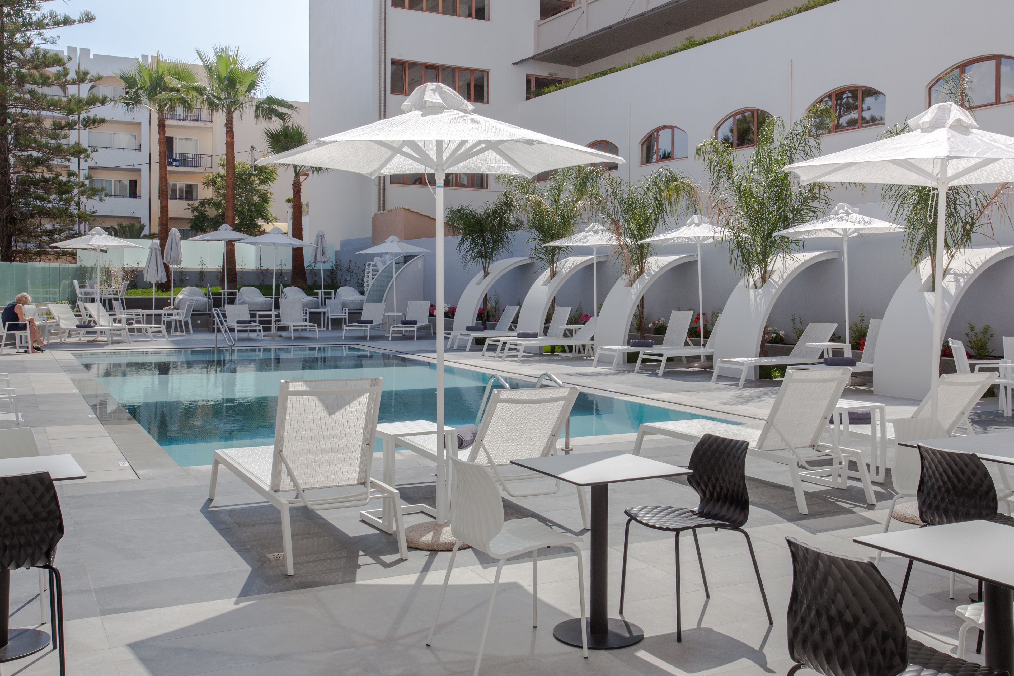 A poolside area with lounge chairs, umbrellas, and a pool.