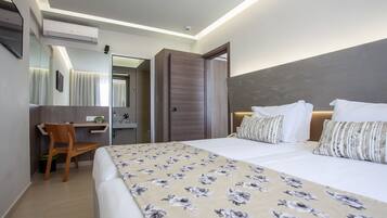 A hotel room with a bed, a desk, a chair, a mirror, and a wardrobe.