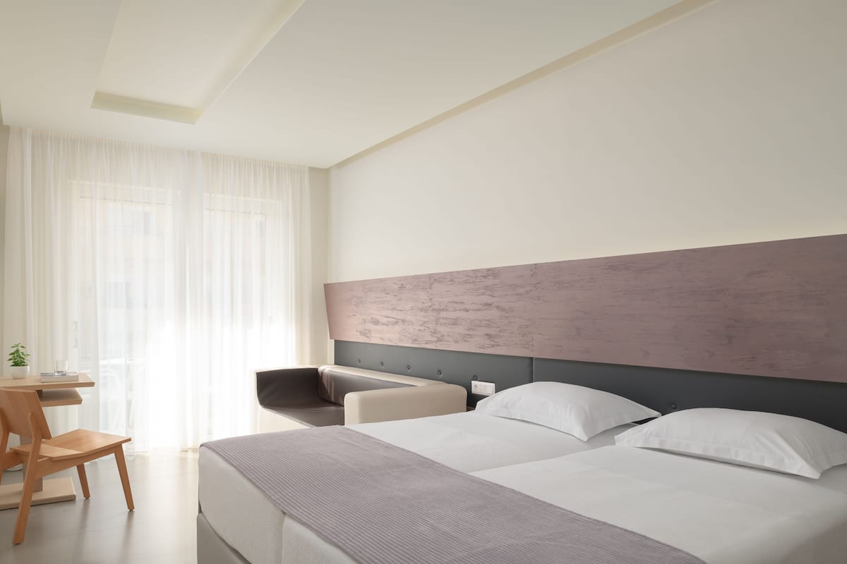 A modern hotel room with a large bed, a desk, and a chair.