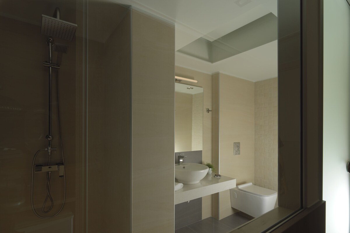 Une salle de bain moderne avec une douche à l’italienne en verre, un lavabo blanc et un grand miroir.