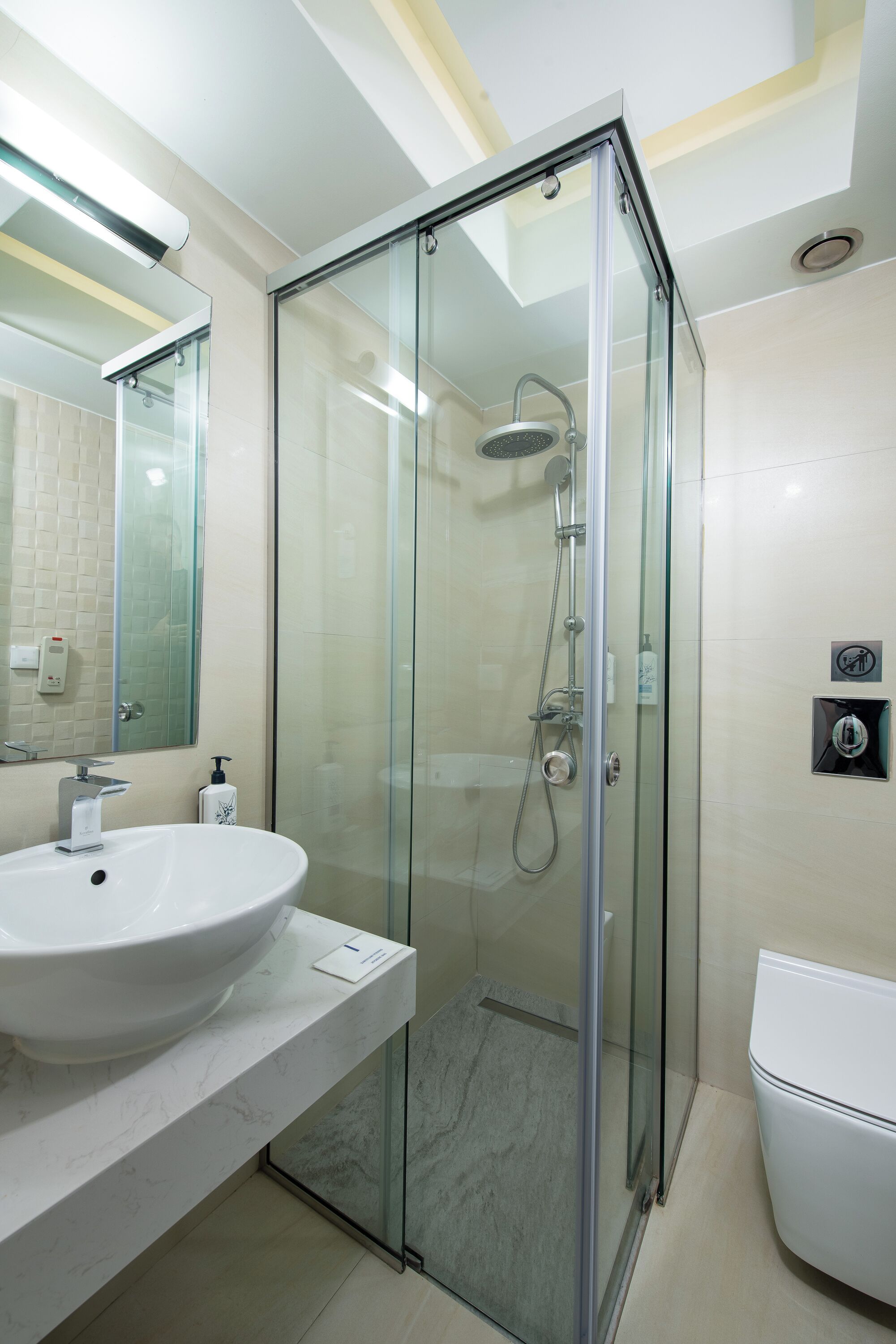 Un baño moderno con ducha envuelta en vidrio, un lavamanos blanco y un inodoro.