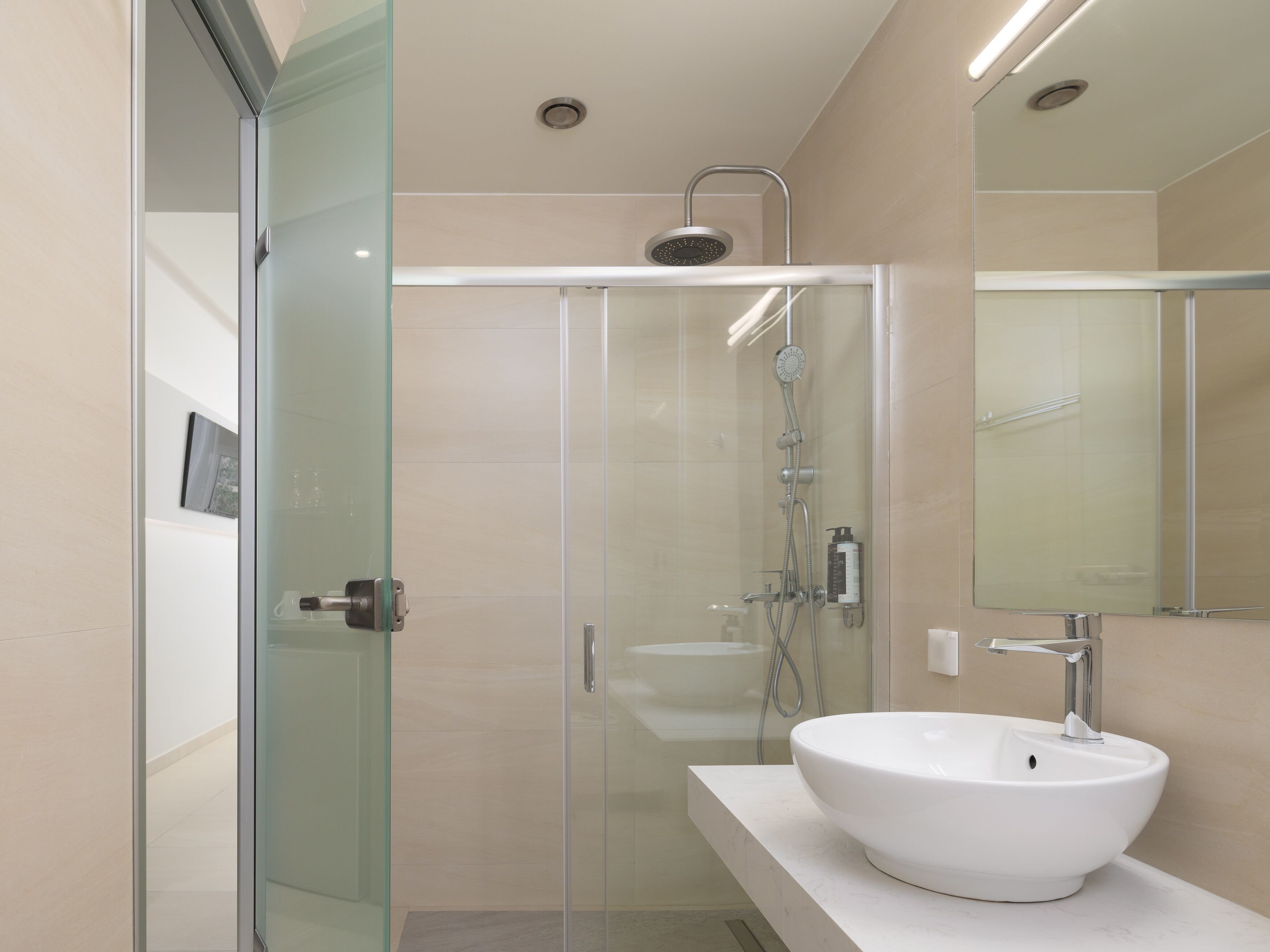 Un baño moderno con cabina de ducha de vidrio, un lavabo blanco y un espejo grande.