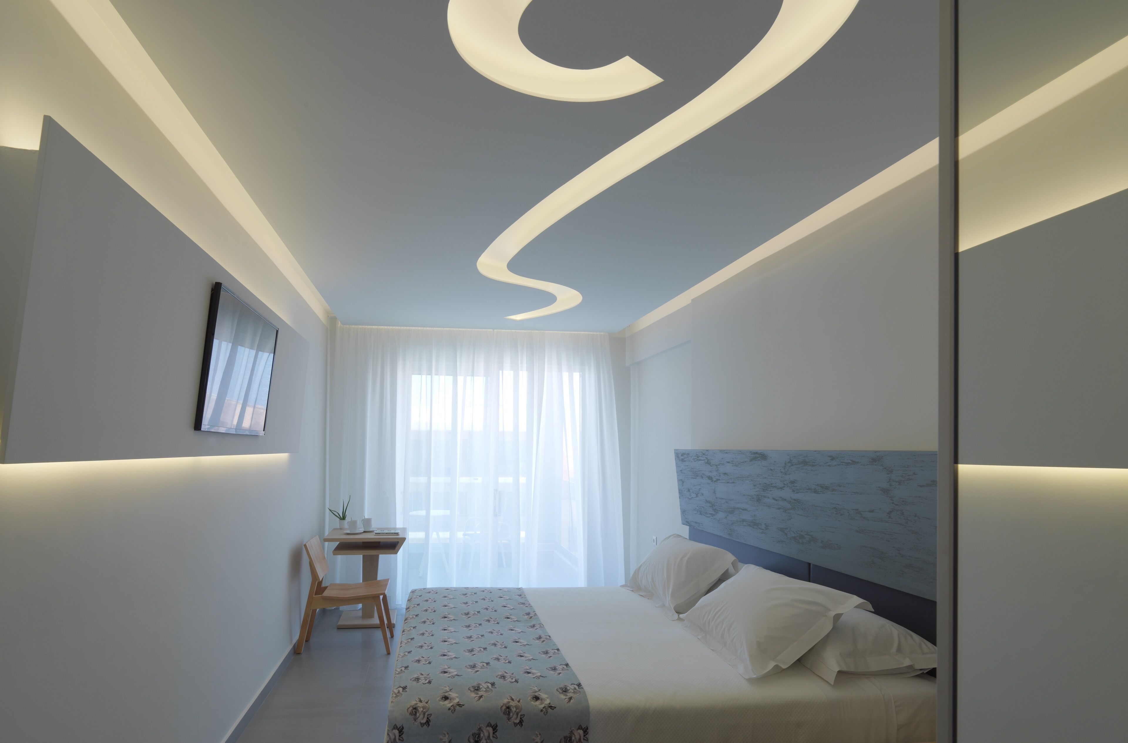 Un dormitorio moderno con una cama, una mesita de noche y un escritorio con una silla.