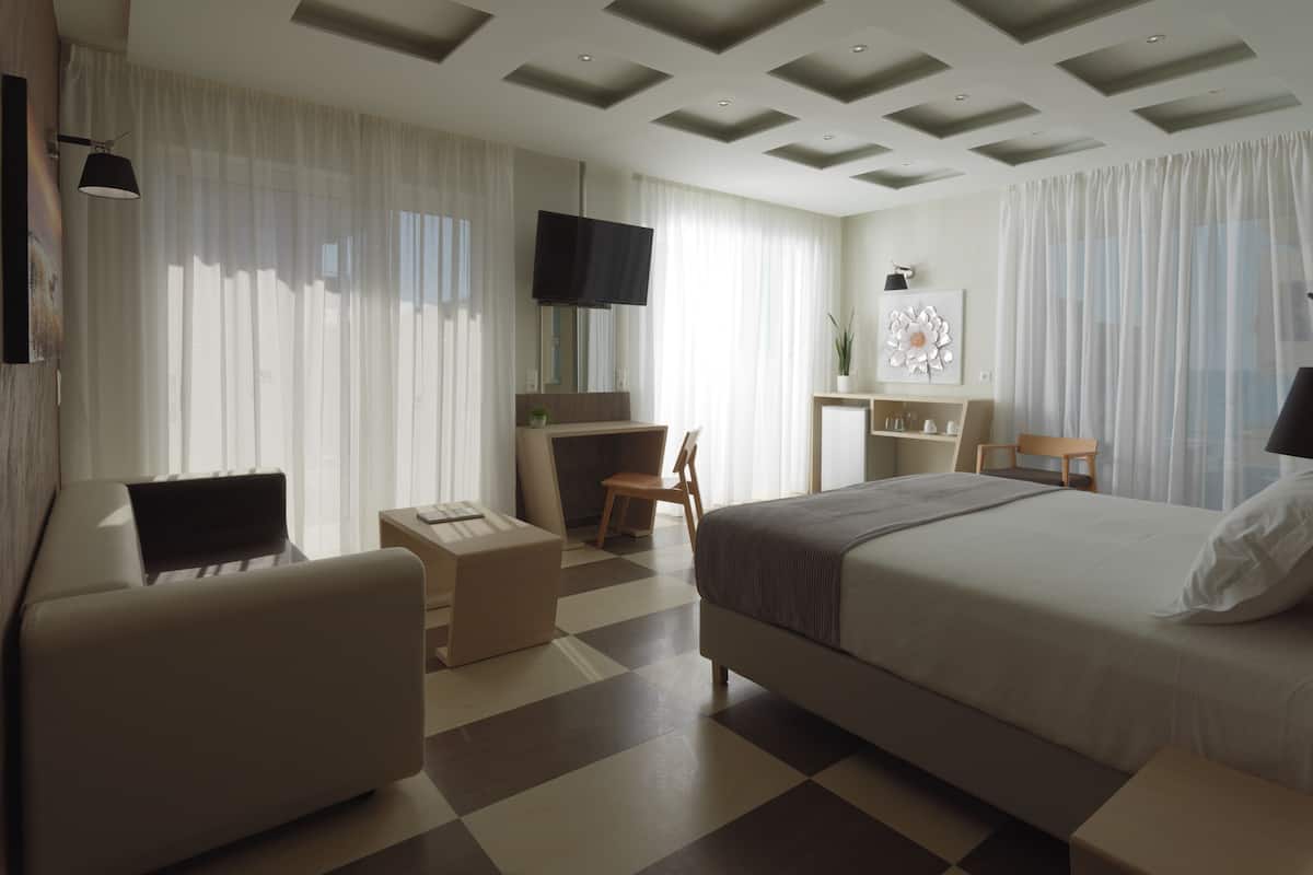 A modern hotel room with a large bed, a desk, a chair, and a television.