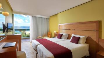 A hotel room with a large bed, a desk, a chair, and a view of the ocean.
