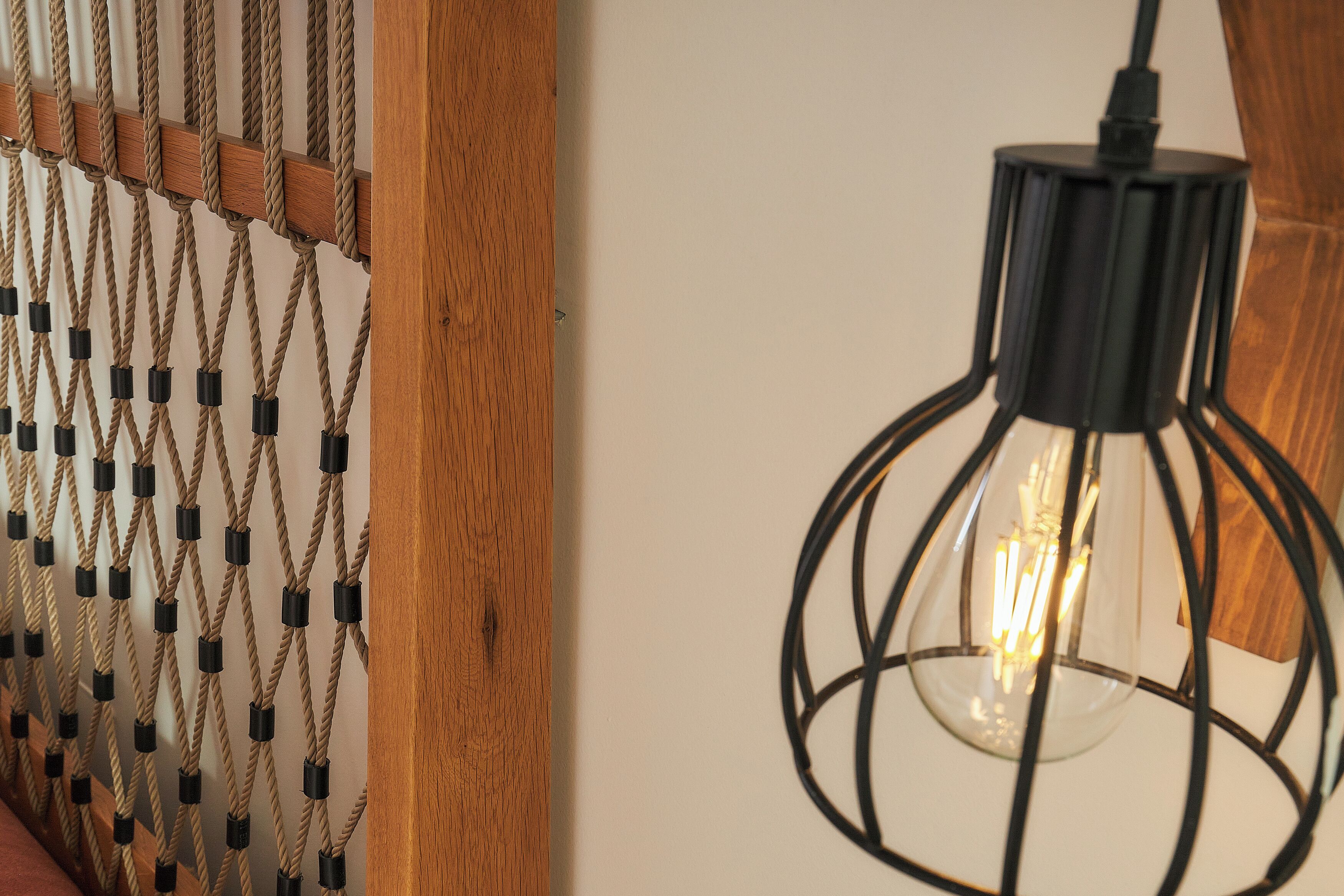 A close-up of a rope wall partition and a modern pendant light fixture.