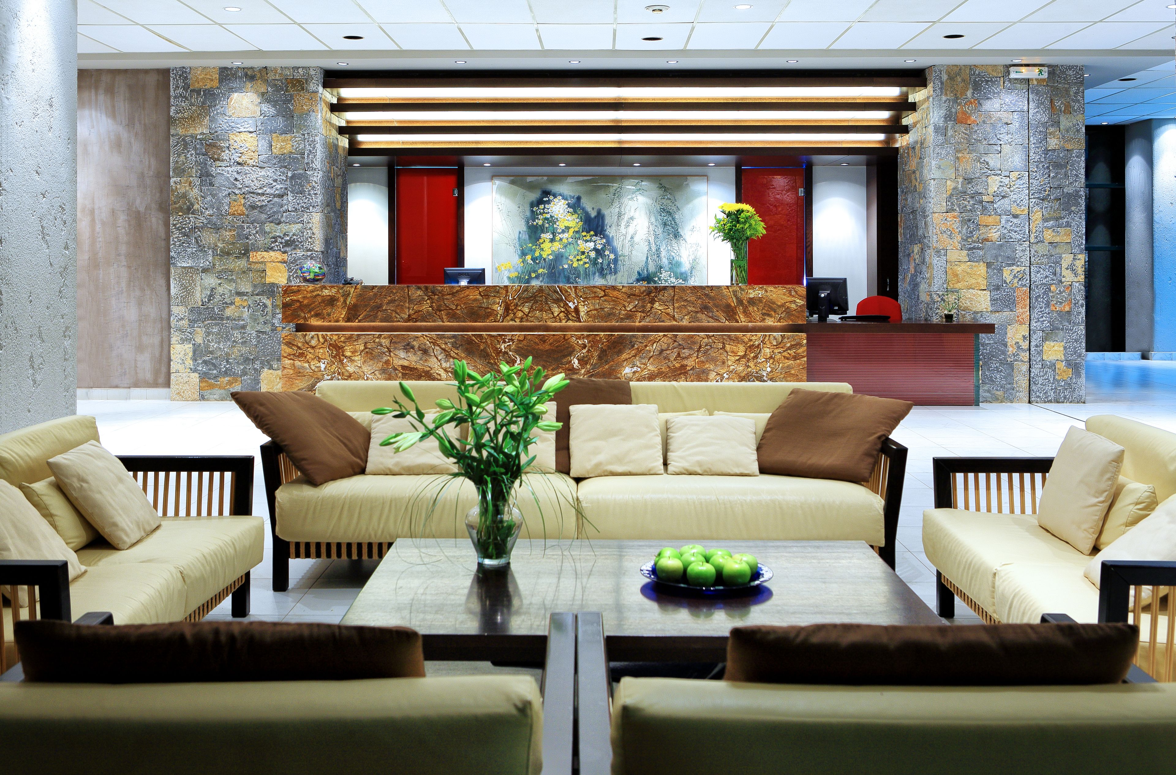 A lobby with a reception desk, sofas, a coffee table, and a decorative wall.