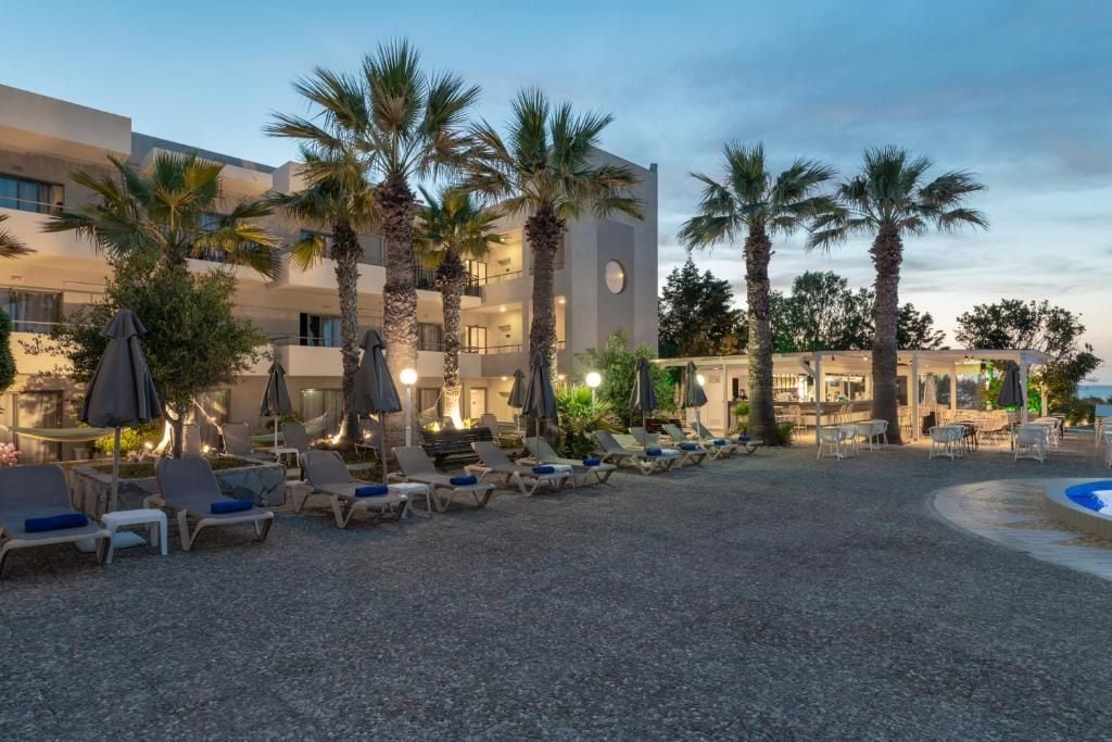 A hotel courtyard with lounge chairs, palm trees, and a pool.
