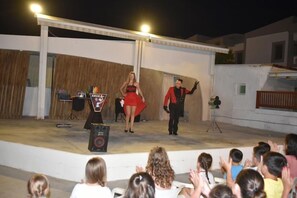 A stage with a performer and a band, an audience, and a DJ setup. - Gouves Bay (Hersonissos)