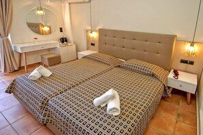 A double bed with patterned bedding, a bedside table with a lamp, a mirror, and a small bench. - Gouves Bay (Hersonissos)