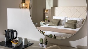 Un dormitorio con un espejo grande, una cama con almohadas, una mesita de noche con un libro, una tetera y dos tazas.