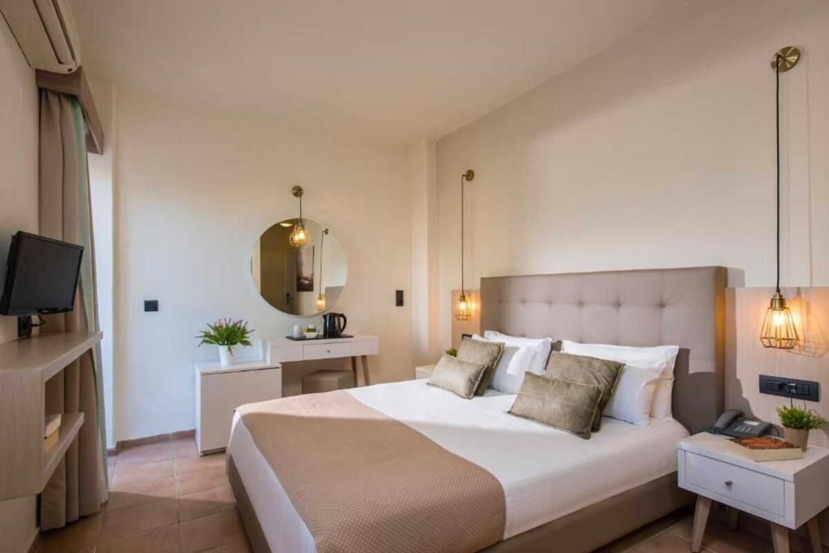 Une chambre d’hôtel comprenant un lit, des tables de chevet, un bureau, une télévision et un miroir.