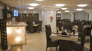 A restaurant with a bar area, multiple dining tables, and chairs. - Hotel Real Rex (León)