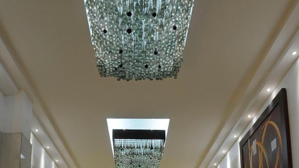 A spacious lobby with a high ceiling, a central reception desk, and a modern chandelier. - Hotel Real Rex (León)