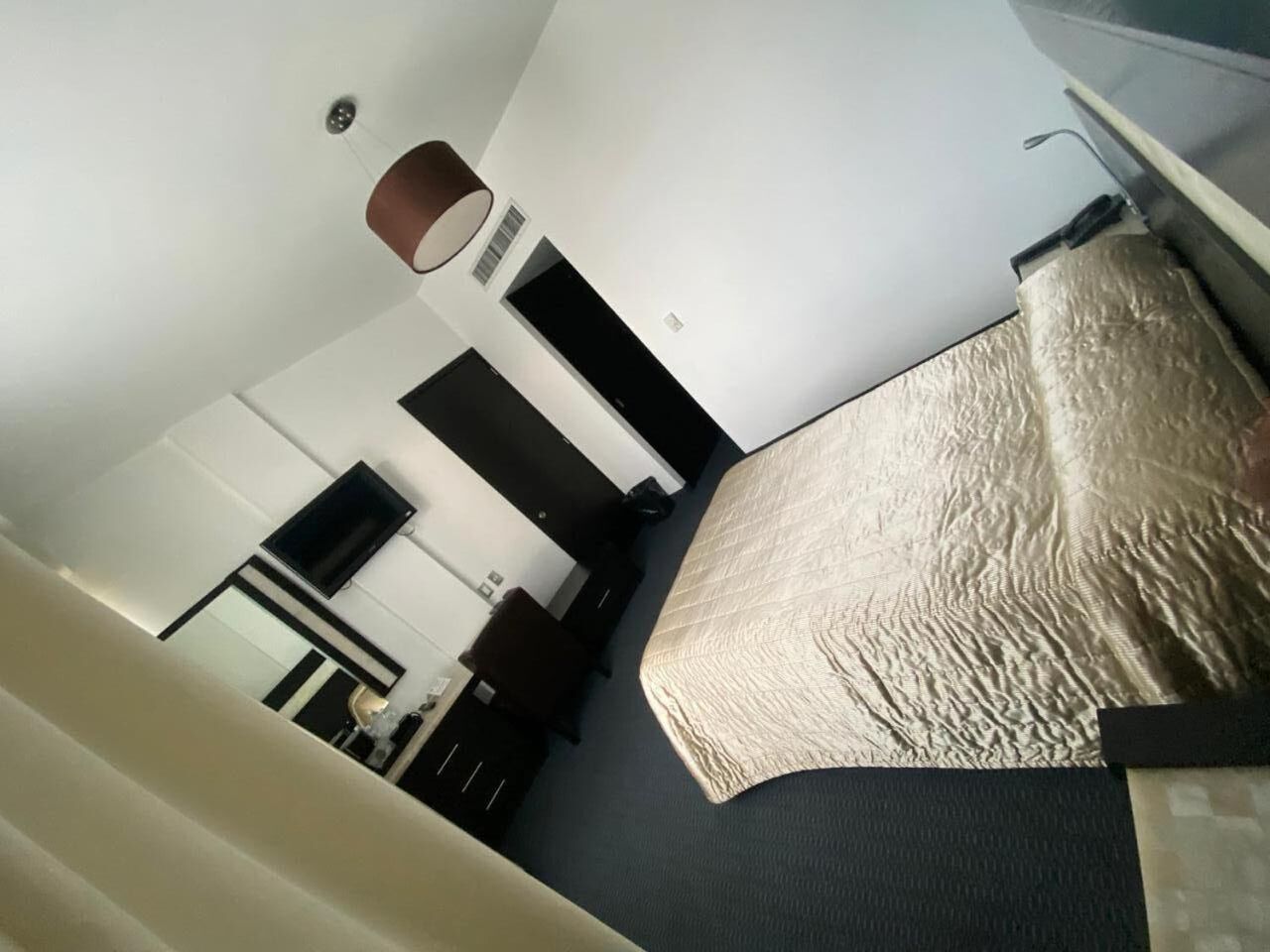 Ein Hotelzimmer mit Bett, Schreibtisch, Stuhl, Lampe und Kleiderschrank.