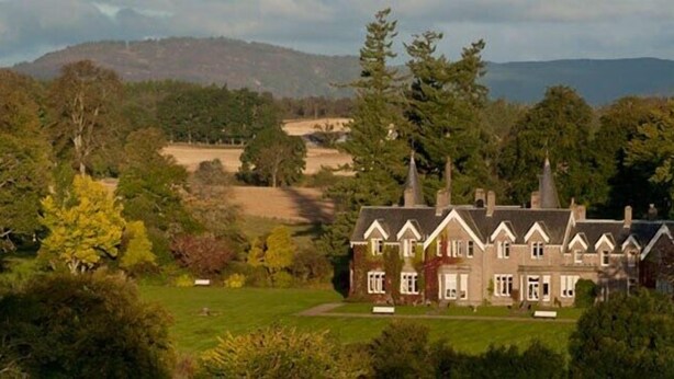 A large, traditional house with multiple chimneys, surrounded by lush greenery and hills in the background. - Ballathie Sportsmans Lodge (Perth)