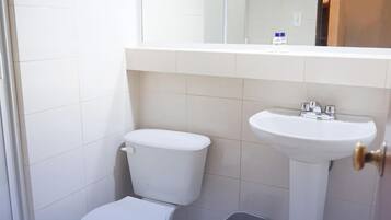 Un baño pequeño con inodoro, lavamanos y cubo de basura.