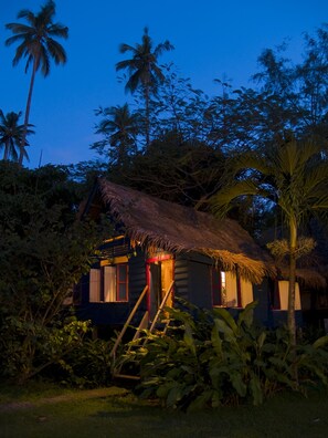 A thatched-roof hut with a wooden staircase leading up to the entrance, surrounded by lush greenery and palm trees. - Bon Ton Resort Langkawi (Langkawi)