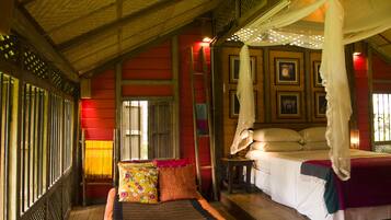 A room with a bed, a nightstand, a window with bars, and a canopy bed.