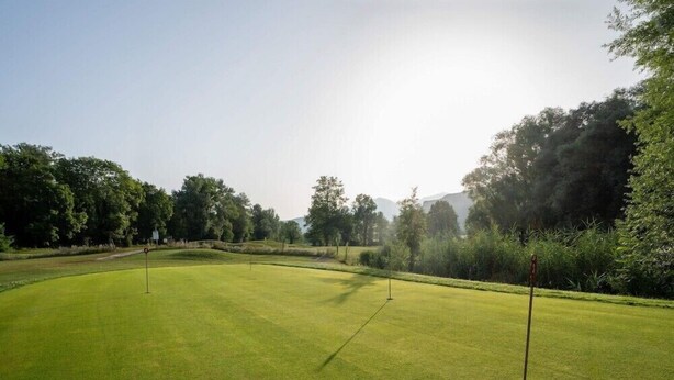 Ein Golfplatz mit gepflegtem Rasen, mehreren Abschlägen und umgebenden Bäumen.