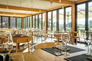 Un restaurante con amplios ventanales, interior de madera y varias mesas de comedor.