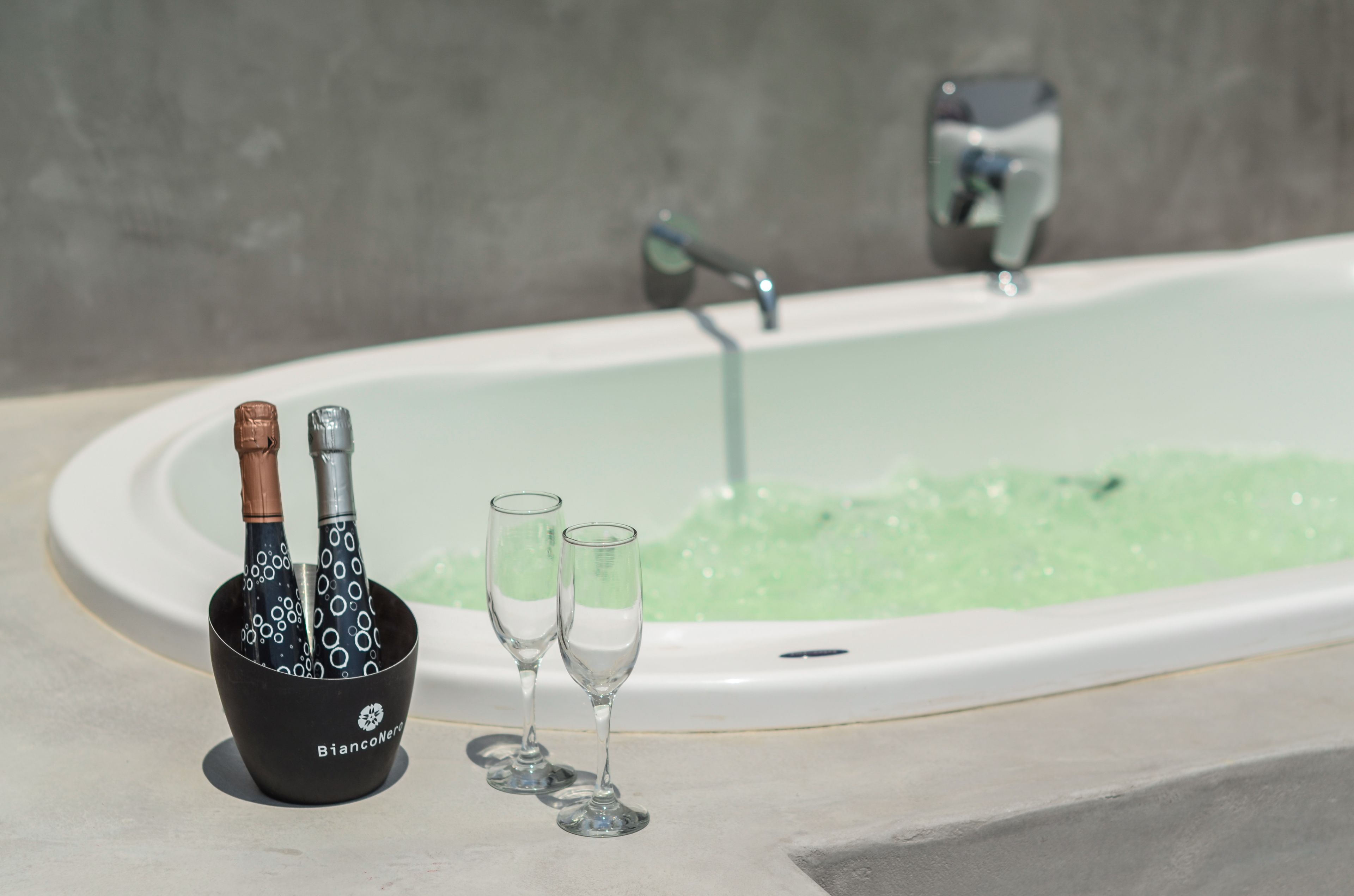 A bathtub with champagne bottles and glasses.