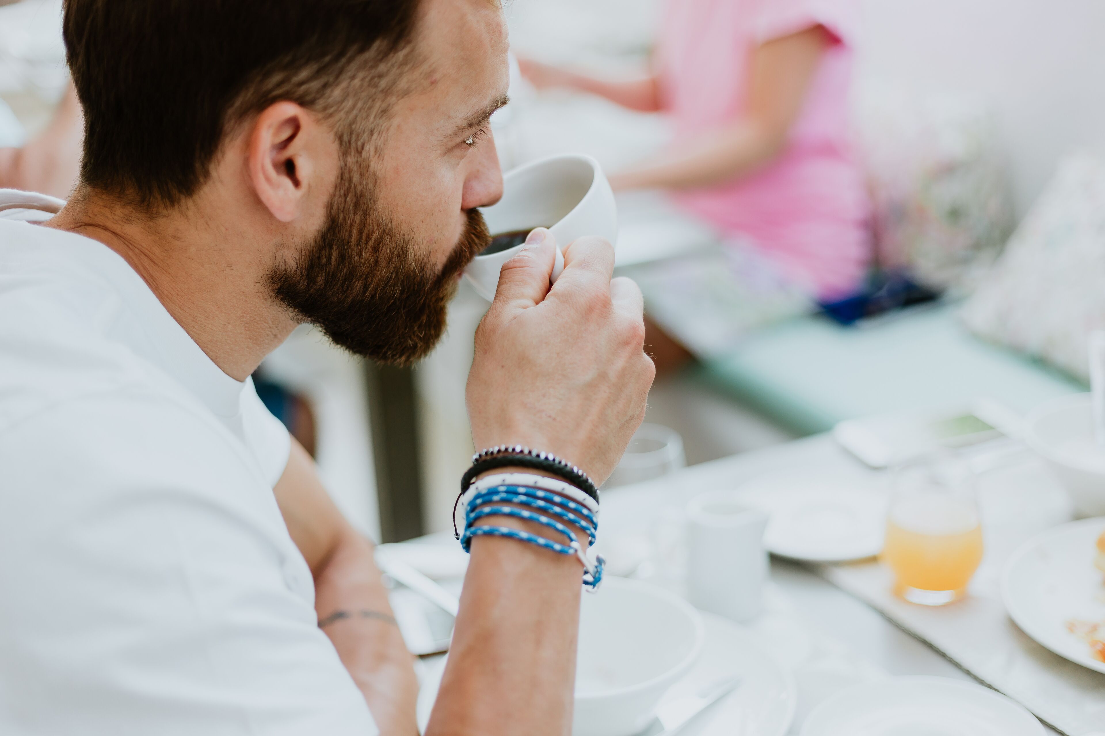 Eine Person sitzt an einem Tisch mit einer Tasse und einem Glas Orangensaft.