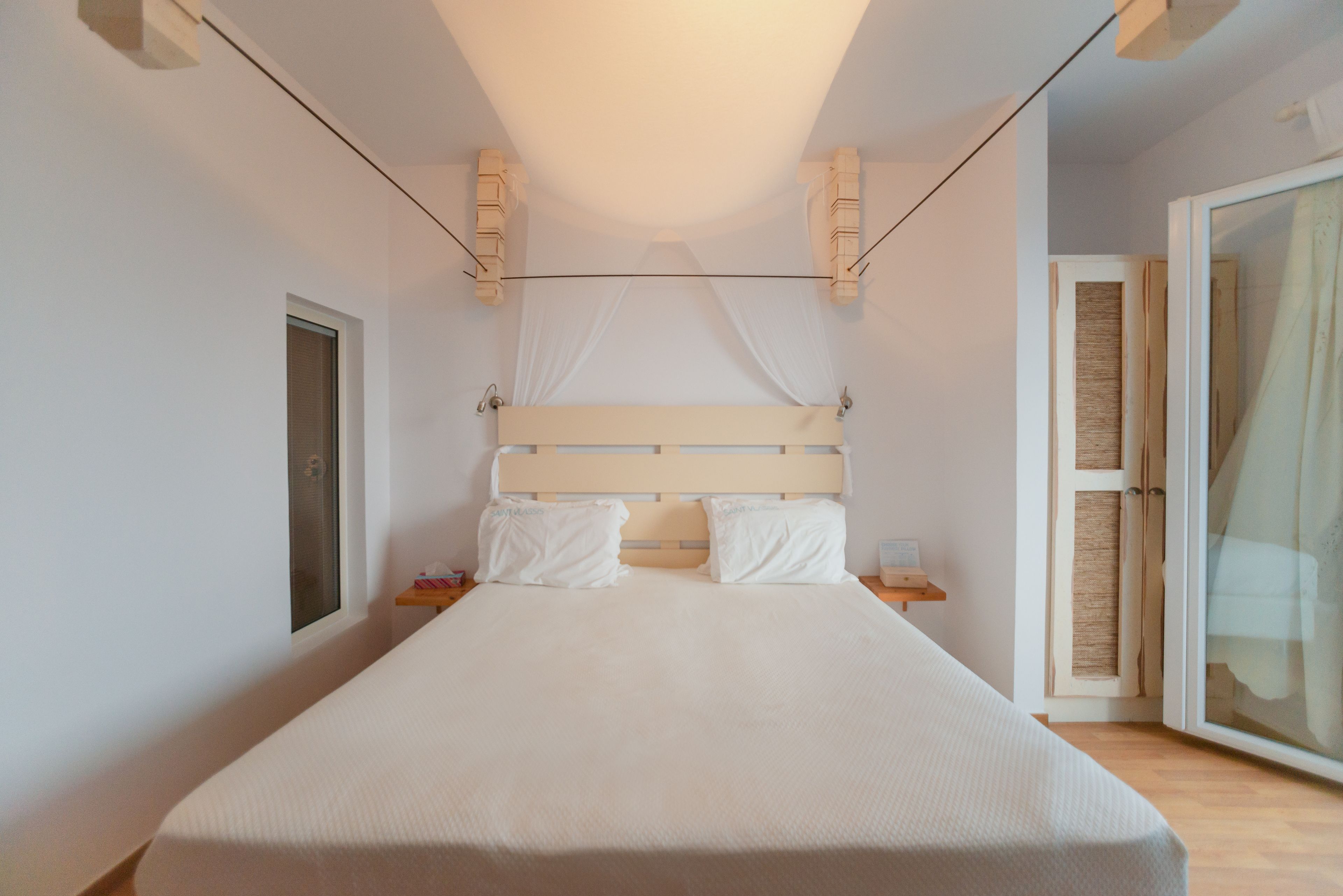 A bedroom with a bed, a nightstand, a window, and a door.